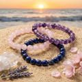 Self-Forgiveness Trio bracelets on golden sand with an ocean sunset